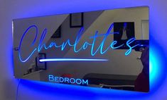 a bathroom mirror that has the word charlotte on it in blue neon lights, with a person taking a selfie