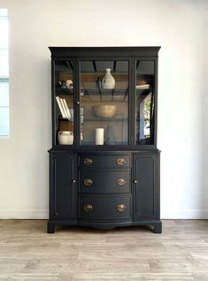 a black china cabinet sitting on top of a hard wood floor