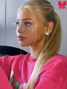 a woman with long blonde hair sitting in front of a computer monitor wearing ear buds