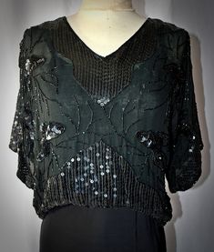 A vintage 1980s retro Edwardian style black 100% silk chiffon pullover blouse with black beading and sequins.  The blouse has a V neckline and wide elbow-length sleeves.  It is a cropped length, with an elastic pulled through a casing at the waist, falling a little higher in the front than the back.  The blouse is fully lined with black silk.  I found no noticeable loose or missing beads or sequins.  38 Inch bust, 34 inches at the waist stretching to 36 inches, 19 inches in length from the shoul V-neck Sequin Blouse For Evening, Silk Party Tops With Sequins, Vintage V-neck Blouse For Party, Vintage V-neck Party Blouse, Vintage V-neck Blouse For Evening, Vintage Silk Evening Tops, Vintage Silk Tops For Evening, Beaded V-neck Tops For Evening, Vintage Silk Blouse For Evening