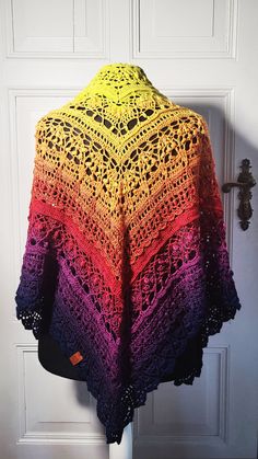 a colorful crocheted shawl hanging on a door