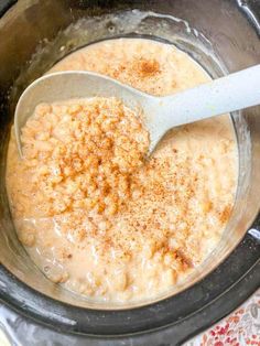 a wooden spoon in a crock pot filled with oatmeal and cinnamon