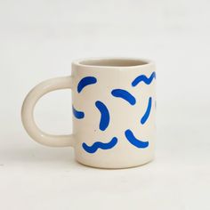 a blue and white coffee cup with swirls on it's side, sitting on a white surface