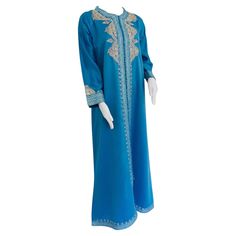 Elegant Moroccan caftan in turquoise blue and silver metallic embroidered trim and front. This long maxi dress kaftan is embroidered and embellished entirely by hand. It’s crafted in Morocco and tailored for a relaxed fit. One of a kind evening Moroccan Middle Eastern gown. The kaftan features a traditional neckline, embellished sleeves. In Morocco, fashion preserves its traditional Islamic style inherited from great civilizations that found their way to Northwest Africa, such as the ottomans an Turquoise Dresses With Resham Embroidery, Turquoise Resham Embroidery Dress For Eid, Turquoise Dress With Resham Embroidery For Eid, Blue Floor-length Kaftan With Resham Embroidery, Blue Resham Embroidery Floor-length Kaftan, Floor-length Blue Kaftan With Resham Embroidery, Elegant Blue Kaftan With Dabka Details, Blue Embroidered Thobe For Wedding, Festive Blue Embellished Abaya