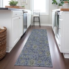 a kitchen with white cabinets and wooden flooring, along with a blue runner rug