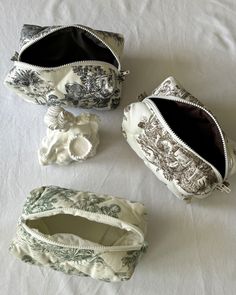 four different purses sitting on top of a white cloth covered tablecloth, with one open and the other closed