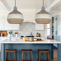 two lights hanging over a kitchen island with stools in front of the counter top