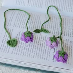 three crocheted flowers are sitting on top of an open book