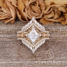 a close up of a diamond ring on a wooden surface with flowers in the background