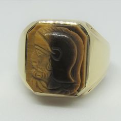 Vintage Gentlemen/Unisex 10kt Yellow Gold Ring with Tiger's Eye Cameo carving of a Roman Soldier motif in relief. Signet style ring setting. This stone is one carving in profile and not assembled. The Rectangle Tiger's Eye Roman Soldier Ring. With this particular carving the chatoyance or cat's eye effect is displayed beautifully and also promotes to the difficulty of using this stone for carving. The Tiger's Eye crystal meaning is associated with courage and confidence which comes from understa Symbolic Carved Jewelry For Formal Occasions, Formal Carved Yellow Gold Signet Ring, Carved 14k Gold Signet Ring For Formal Occasions, Carved Signet Ring In 14k Gold For Formal Occasions, Formal Carved Signet Ring In 14k Gold, Carved 14k Gold Signet Ring For Anniversary, Formal Carved Yellow Gold Rings, Formal Yellow Gold Carved Rings, Formal Carved Rings In 14k Gold