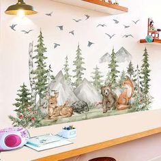 a wall mural with animals in the woods and birds flying above it, behind a desk