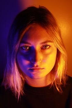 a woman with long blonde hair and blue eyes is looking at the camera while wearing a black shirt