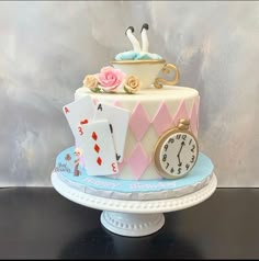 a cake decorated with playing cards and a clock