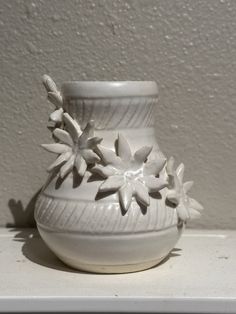 a white vase sitting on top of a shelf