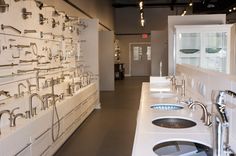 a row of sinks in a bathroom next to a wall full of faucets