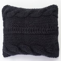 a black knitted pillow sitting on top of a white table