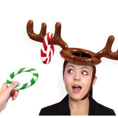 a woman wearing reindeer antlers and holding candy canes in front of her head