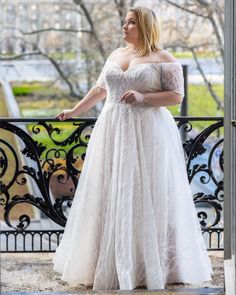 a woman in a white wedding dress standing on a balcony looking off into the distance