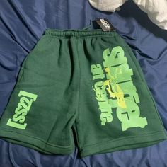 A Hole In One Pocket Green Bottoms With Letter Print For Streetwear, Green Summer Sports Bottoms, Green Spring Streetwear Bottoms, Summer Streetwear Bottoms With Letter Print, Sporty Graphic Print Bottoms For Summer, Sporty Graphic Print Summer Bottoms, Casual Green Short Bottoms, Green Summer Bottoms For Leisure, Green Bottoms For Leisure In Summer