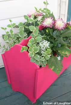 a pink planter filled with flowers sitting on top of a porch