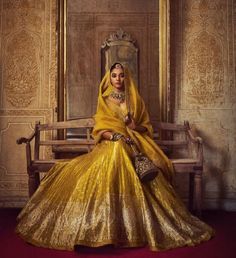 a woman sitting on top of a wooden bench wearing a yellow dress and holding a purse