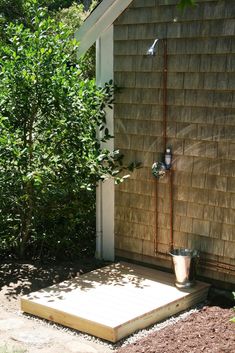 a small wooden platform in front of a house with a potted plant on it