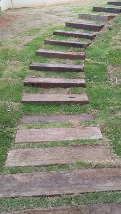 a set of wooden steps leading up to the top of a grassy hill in front of a house