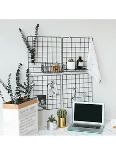 a laptop computer sitting on top of a desk next to a planter and potted plants