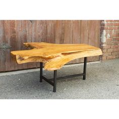 a wooden table sitting on top of a cement floor next to a brick wall and door