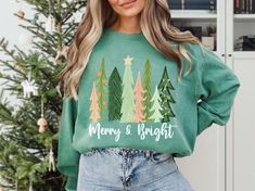 Comfort Colors® Merry and Bright Sweatshirt, Xmas Shirts, Family Christmas Shirts, Christmas Sweatshirt for Women, Merry Christmas Sweater This charming Christmas sweatshirt showcases hand-painted Christmas trees, each unique and festive, arranged in a whimsical pattern. The phrase "Merry and Bright" is elegantly displayed in a joyful script, adding a personal and artistic touch to the design. The soft fabric provides warmth and comfort, while the vibrant green trees and colorful accents make it Holiday Green Cotton Sweatshirt, Green Cotton Holiday Sweatshirt, Relaxed Fit Long Sleeve Holiday T-shirt, Relaxed Fit Long Sleeve T-shirt For Holiday, Green Long Sleeve T-shirt For Holiday, Green Christmas Crew Neck Sweatshirt, Green Christmas Sweatshirt With Letter Print, Christmas Green Sweatshirt With Graphic Print, Christmas Green Graphic Print Sweatshirt