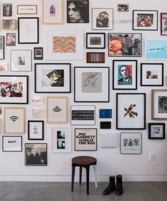 a white wall covered in lots of pictures and framed photos next to a desk with a computer on it