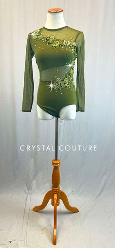 a green bodysuit on a mannequin with gold sequins and stars