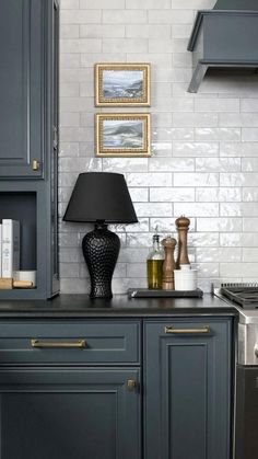 a kitchen with blue cabinets and white subway backsplashes, gold trim around the edges