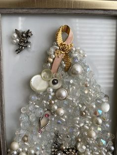 a christmas tree made out of buttons and other items in a shadow box with a ribbon