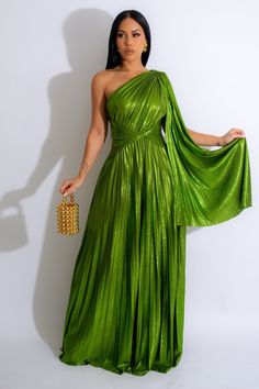 a woman in a green dress is holding a purse and posing for the camera with her hand on her hip