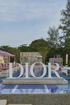 an outdoor swimming pool with chairs and umbrellas in the background that reads dior