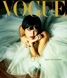 a woman laying on top of a wooden floor wearing a white dress and holding her hand near her face