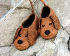 a pair of slippers with a dog face on them sitting on the ground next to some rocks