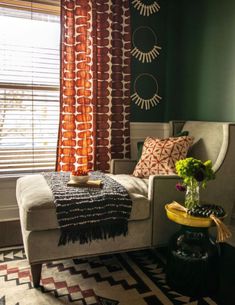 a bedroom with green walls, white bedding and colorful curtains on the window sill