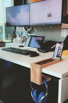 a computer desk with two monitors and headphones on it