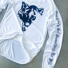 a white long sleeved shirt with a wolf on the front and writing on the back