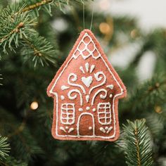 a gingerbread house ornament hanging from a christmas tree