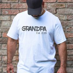 Grandpa Est. Shirt PLEASE CHECK THE SIZING.  Shirts and pants are unisex size and run large on most women. DESIGN DETAILS: **Sublimation creates a vintage/faded look. Fit: Unisex- please check size chart prior to ordering. DESIGN DETAILS: * Shirt design is sublimation. * Professionally heat pressed. * Each shirt is made to order.  * The pictures are mockups and design placement and color may vary slightly. * Sublimation may be more vintage/faded than it appears in the mockup. SHIRT DETAILS: *Tri-blend 50/25/25-poly/cotton/rayon) , 65/35 poly cotton blend or 50/48 poly cotton blend depending on color and availability. * We HIGHLY recommend verifying your size with the size chart in the listing photos above.  * A Tip For Sizing: Take your favorite fitting t-shirt and measure. Take those meas White Relaxed Fit Shirt For Family Events, White Relaxed Fit Shirt For Family Occasions, White T-shirt With Text Print For Family Reunion, White Short Sleeve Shirt For Family Reunion, White Shirt With Text Print For Family, White T-shirt For Father's Day Family Reunion, White Relaxed Fit Shirt For Family Reunion, Father's Day Shirt With Name Print And Relaxed Fit, Father's Day Shirt With Name Print In Relaxed Fit