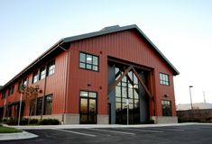 an empty parking lot in front of a large red building with windows and doors on each side