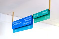 two street signs hanging from the ceiling in front of a white wall with blue lettering