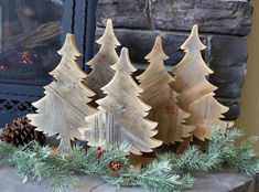 three wooden christmas trees sitting next to a fireplace