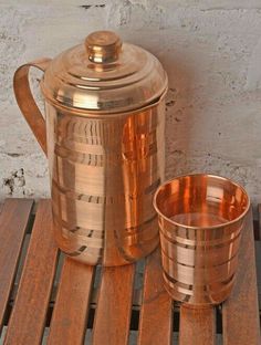 a copper colored tea pot and cup on a wooden table