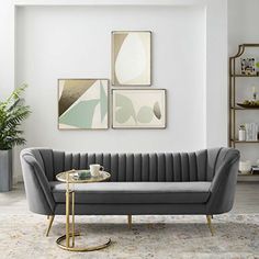 a living room with white walls and grey couches in front of paintings on the wall