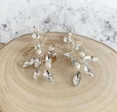 three pairs of crystal earrings on top of a wooden slice