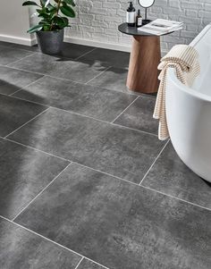 a bath tub sitting on top of a tiled floor next to a white brick wall